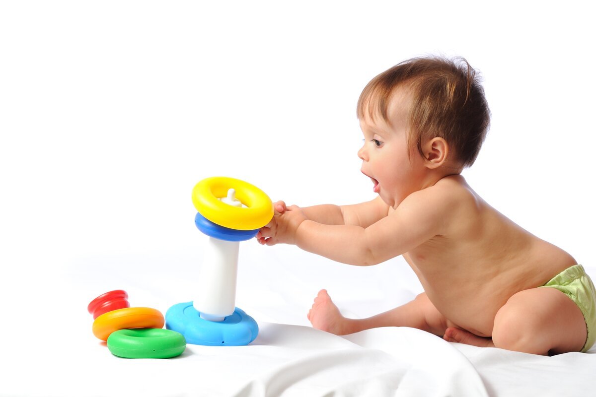 Best developmental toys for babies in India - a baby delighted while playing with a colourful ring stacking toy