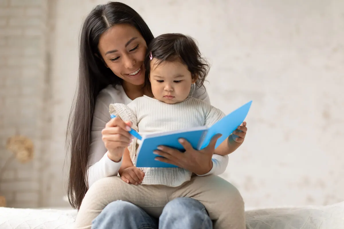 Raising a bilingual child - a mother and her toddler sharing a picture book together at home