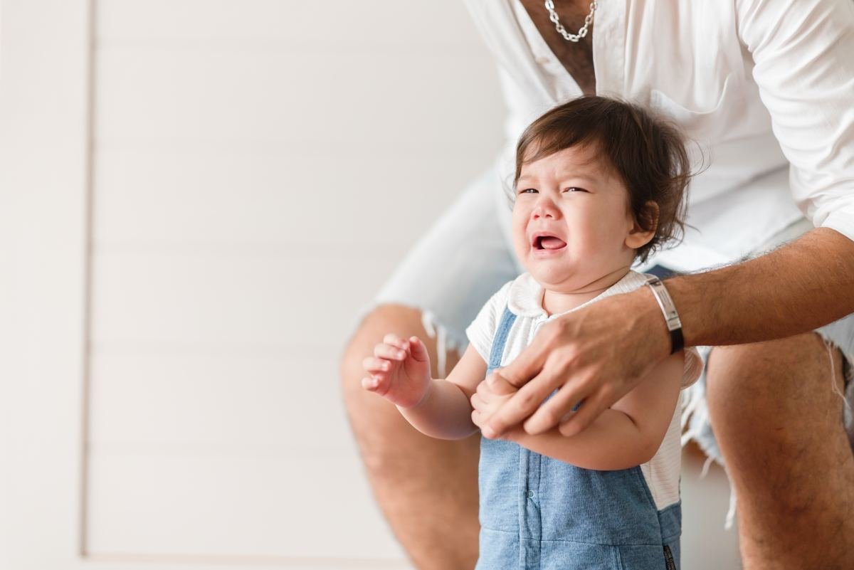 How to handle toddler tantrums - a mother calmly comforting her crying toddler at home