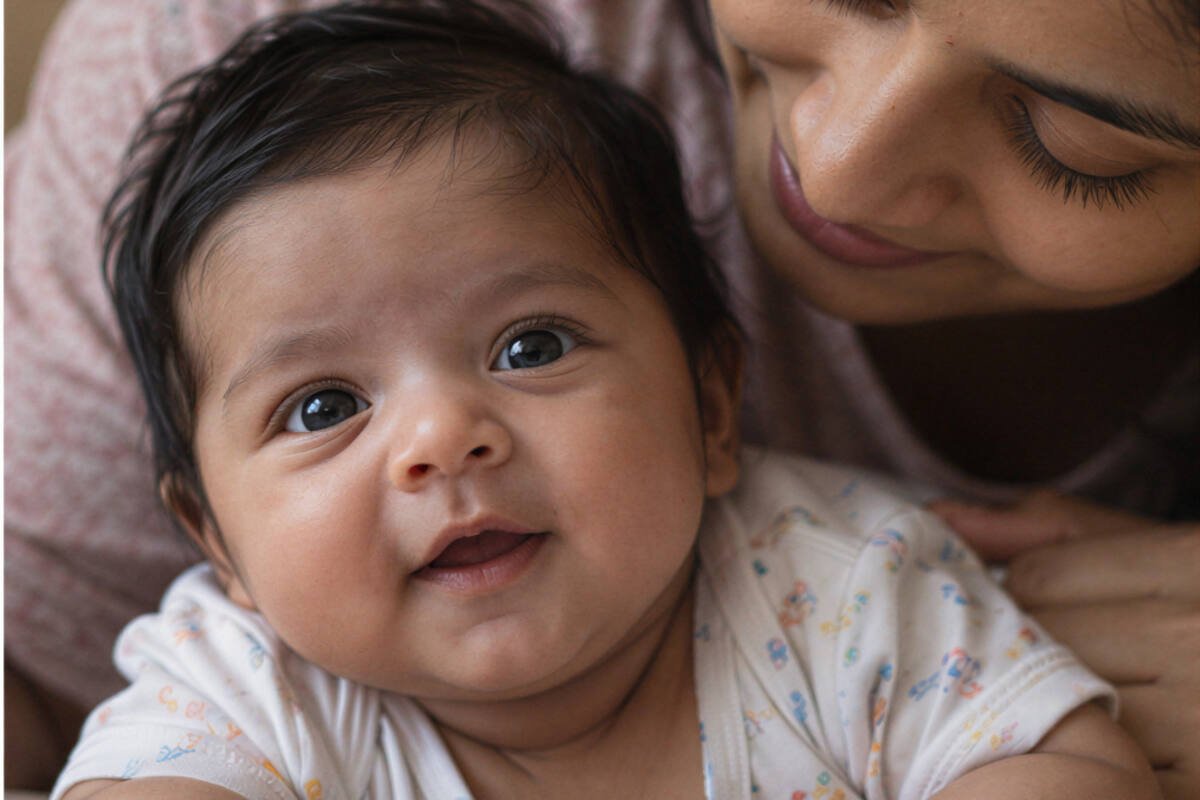 Premature baby care at home - a newborn baby looking up as mum leans in close